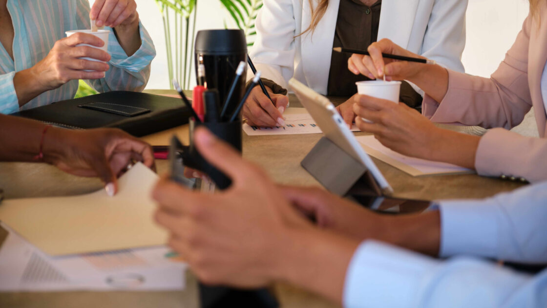 Rethink Fundraising with These Four Questions. Charity meeting. For people sat around a table